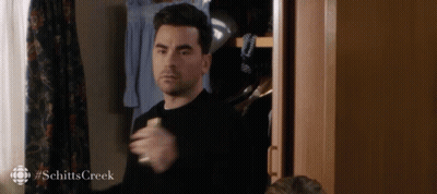 A Man In A Black Shirt Is Standing In Front Of A Closet With #Schittscreek Written On The Bottom GIF