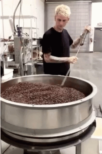 A Man In A Black Shirt Is Standing In Front Of A Large Metal Bowl GIF