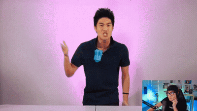 A Man In A Black Shirt Is Standing In Front Of A Pink Background GIF