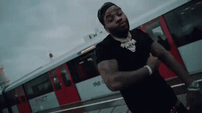 A Man In A Black Shirt Is Standing In Front Of A Red Train . GIF