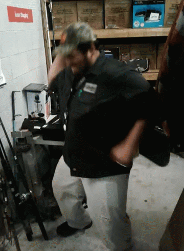 A Man In A Black Shirt Is Standing In Front Of A Sign That Says " Low Sliding " GIF