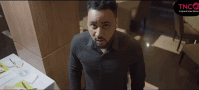 A Man In A Black Shirt Is Standing In Front Of A Table With A Sign That Says Tnco On It GIF