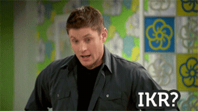 A Man In A Black Shirt Is Standing In Front Of A Wall With Flowers On It And Says Ikr GIF