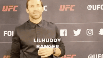 A Man In A Black Shirt Is Standing In Front Of A Wall With Ufc Logos On It GIF