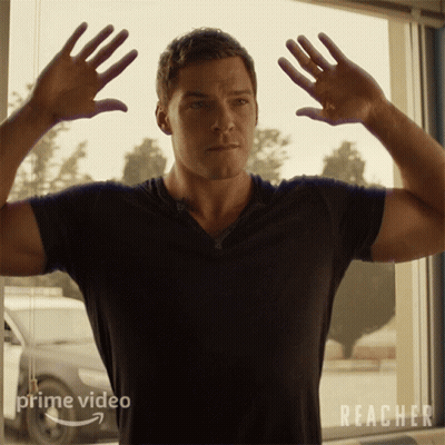 A Man In A Black Shirt Is Standing In Front Of A Window With Reacher Written On It GIF