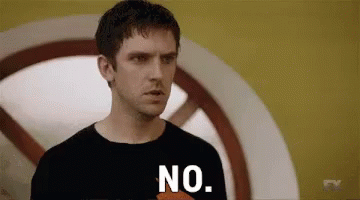 A Man In A Black Shirt Is Standing In Front Of A Yellow Wall And Saying No . GIF