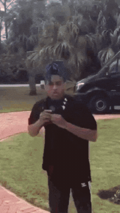 A Man In A Black Shirt Is Standing In The Grass GIF