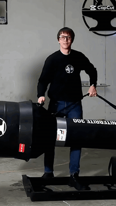 A Man In A Black Shirt Is Standing Next To A Large Black Barrel That Says Integrite 300 On It GIF