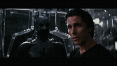 A Man In A Black Shirt Is Standing Next To A Man In A Black Suit . GIF