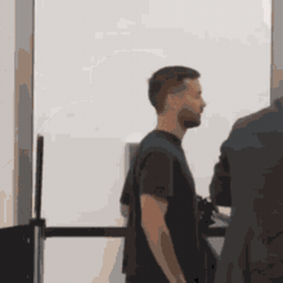 A Man In A Black Shirt Is Standing Next To A Man In A Suit GIF
