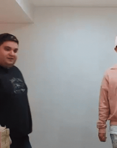 A Man In A Black Shirt Is Standing Next To A Woman In A Pink Sweater . GIF