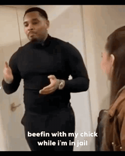 A Man In A Black Shirt Is Standing Next To A Woman In A Room . GIF