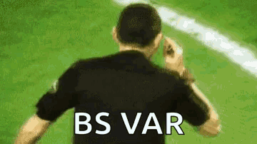 A Man In A Black Shirt Is Standing On A Soccer Field With The Words `` Bs Var '' Written On His Back . GIF