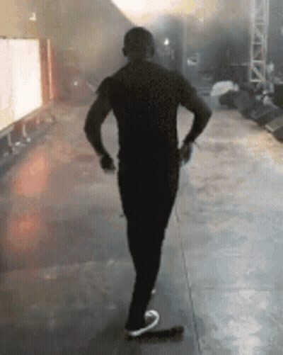 A Man In A Black Shirt Is Standing On A Stage . GIF