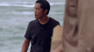 A Man In A Black Shirt Is Standing On The Beach Looking At The Ocean . GIF