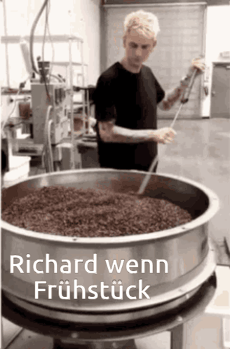 A Man In A Black Shirt Is Stirring Something In A Large Metal Bowl With The Words Richard Wenn Fruhstück Written Below H GIF