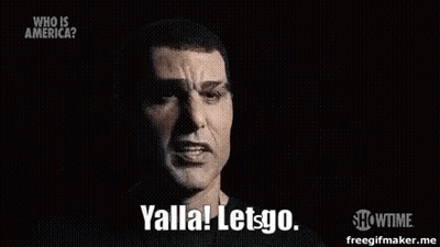 A Man In A Black Shirt Is Talking In A Dark Room And Saying Yalla Let Go . GIF