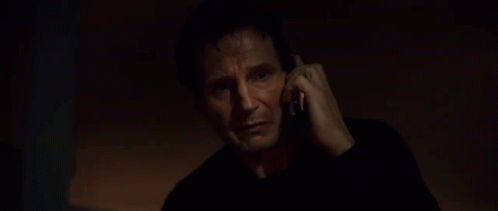A Man In A Black Shirt Is Talking On A Cell Phone . GIF
