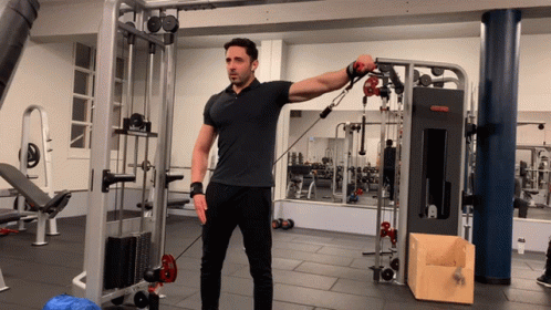 A Man In A Black Shirt Is Using A Machine That Says ' Reebok ' On It GIF