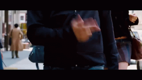 A Man In A Black Shirt Is Walking Down The Street GIF