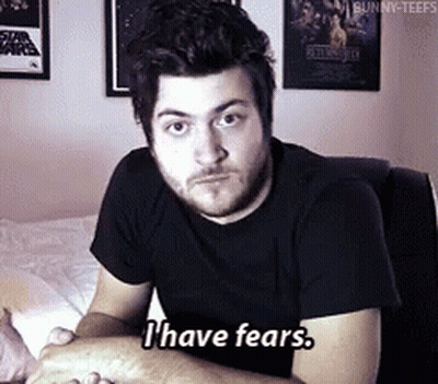 A Man In A Black Shirt Says " I Have Fears " While Sitting On A Bed GIF