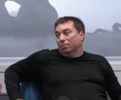 A Man In A Black Shirt Sits In A Chair GIF