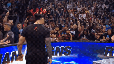 A Man In A Black Shirt Stands In Front Of A Crowd Behind A Sign That Says Ns GIF