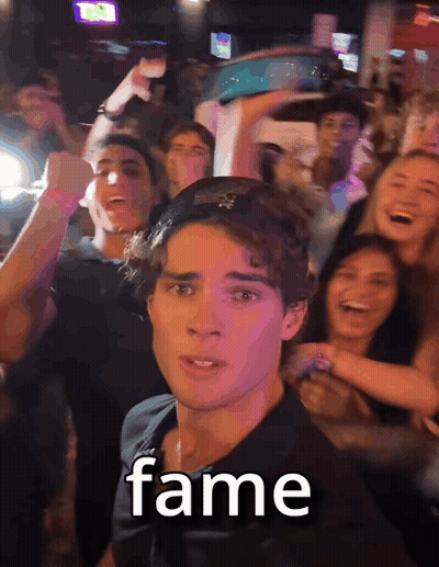 a man in a black shirt stands in front of a crowd with the word fame written on his face