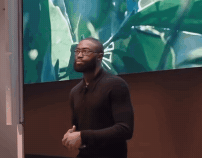 A Man In A Black Shirt Stands In Front Of A Green Screen GIF