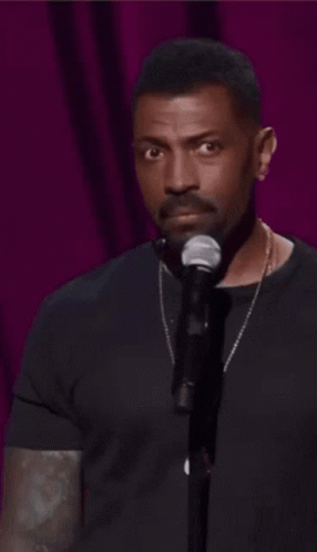 A Man In A Black Shirt Stands In Front Of A Microphone And Says " Welp " In White Letters GIF