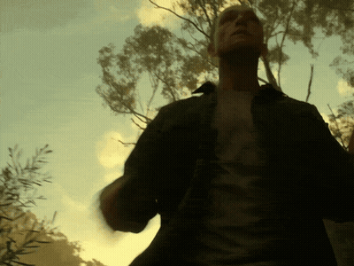 A Man In A Black Shirt Stands In Front Of A Tree GIF