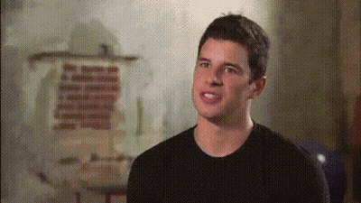 A Man In A Black Shirt Stands In Front Of A Wall With A Painting On It GIF