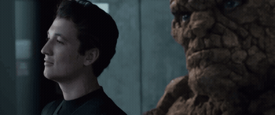 A Man In A Black Shirt Stands Next To A Statue Of A Face GIF