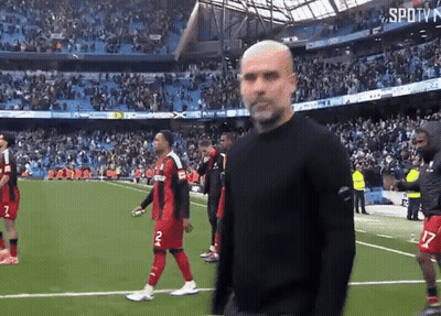 A Man In A Black Shirt Stands On A Soccer Field With Players Wearing Red And Black Jerseys With The Number 2 On Them GIF