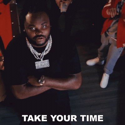 A Man In A Black Shirt With A Necklace That Says Take Your Time GIF