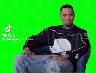 A Man In A Black Shirt With A Skull On It Is Sitting In A Chair On A Green Screen . GIF