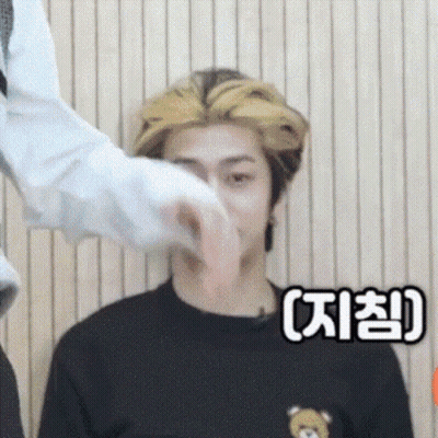 A Man In A Black Shirt With A Teddy Bear On It Is Being Touched By Another Man . GIF