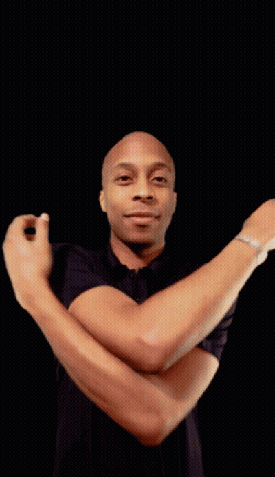 A Man In A Black Shirt With His Arms Crossed Looks At The Camera GIF