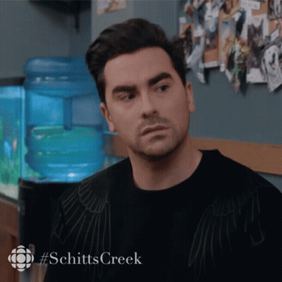 A Man In A Black Shirt With #Schitts Creek On The Bottom GIF