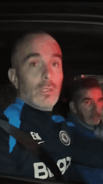 A Man In A Black Shirt With The Letter B On It Is Sitting In A Car . GIF