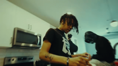 A Man In A Black Shirt With The Letter R On It Is Cooking GIF