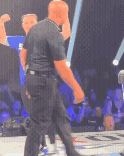 A Man In A Black Shirt With The Letter S On It Stands In Front Of A Crowd GIF
