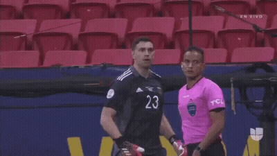 A Man In A Black Shirt With The Number 20 On It Is Standing Next To Another Man In A Pink Shirt GIF