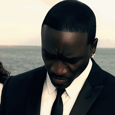 A Man In A Black Suit And Tie Looks Down GIF