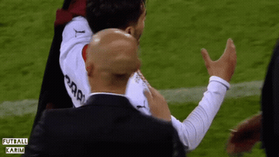 A Man In A Black Suit Holds A Soccer Player In A White Jersey That Says Karim GIF
