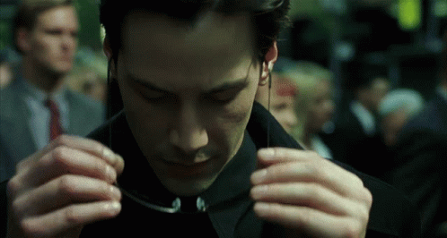 A Man In A Black Suit Is Adjusting His Sunglasses GIF