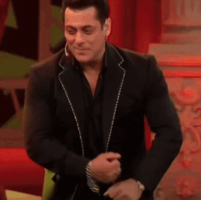 A Man In A Black Suit Is Dancing And Smiling . GIF