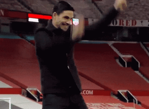 A Man In A Black Suit Is Dancing In A Stadium . GIF