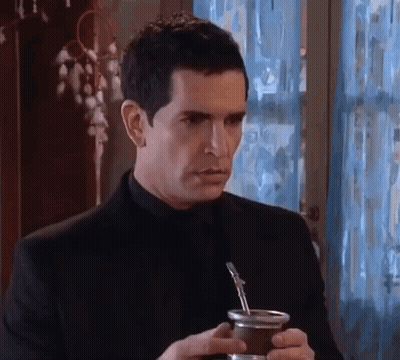 A Man In A Black Suit Is Holding A Cup Of Yerba Mate . GIF