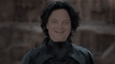 A Man In A Black Suit Is Holding A Knife Over His Head . GIF